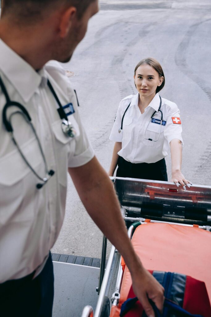 Paramedics prepare gurney and medical equipment for emergency response.