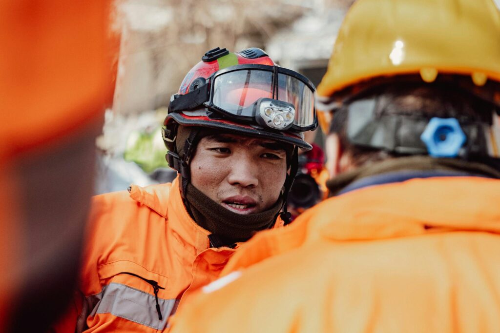 Two rescue workers in helmets and safety gear discussing the emergency response plan.